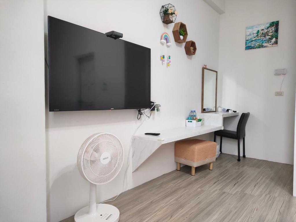 Chaozhou上海民宿的客房设有带风扇的书桌和墙上的电视。