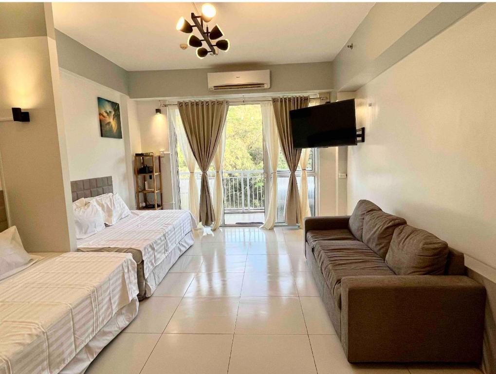 纳苏格布Pico de Loro Miranda Family Beach Condo max 6 pax with fiber internet的客房设有两张床、一张沙发和一台电视。