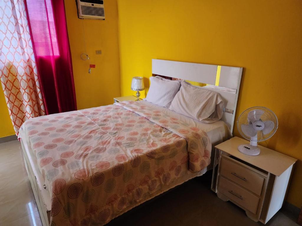 Super Two Bedroom Penthouse in Peguy-Ville的一间卧室配有一张床,还有一个带风扇的床头柜。