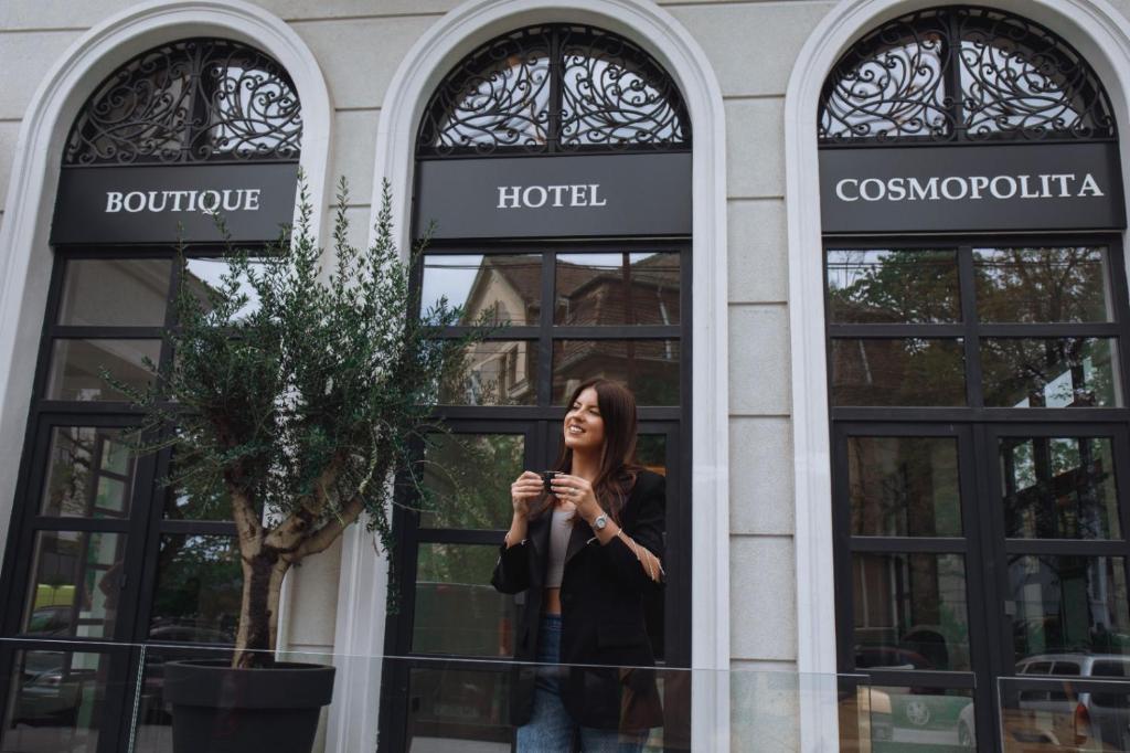 蒂米什瓦拉Cosmopolita Boutique Hotel的站在旅馆前面的女人