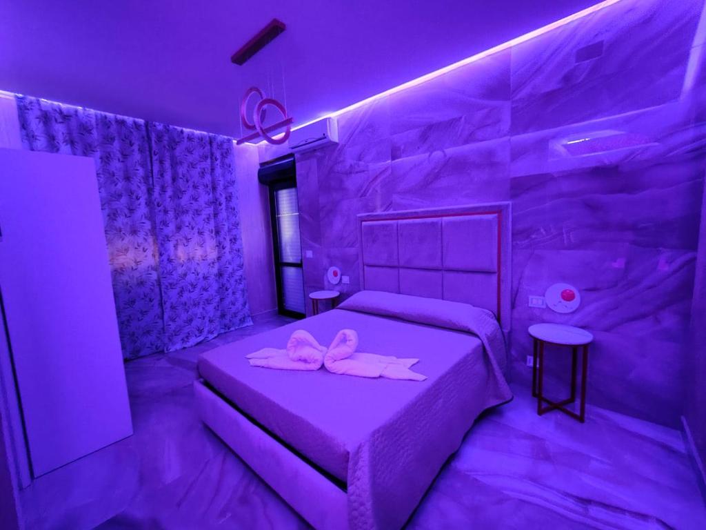 福贾B&B MaisonAlysie的紫色卧室,配有一张带两个粉红色弓的床