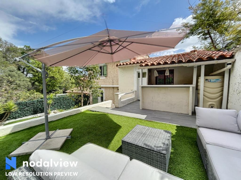 卢贝新城Villa Azurella的房屋庭院内带遮阳伞的庭院