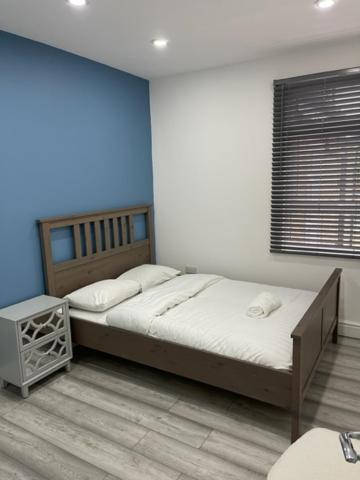 伦敦EAST LONDON APARTMENTS SELF check in的一间卧室设有一张大床和蓝色的墙壁