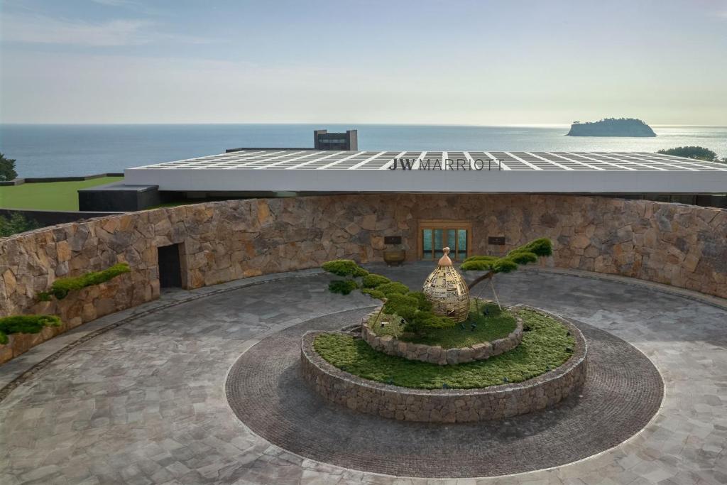 西归浦市JW Marriott Jeju Resort & Spa的一座以海洋为背景的建筑前方的喷泉