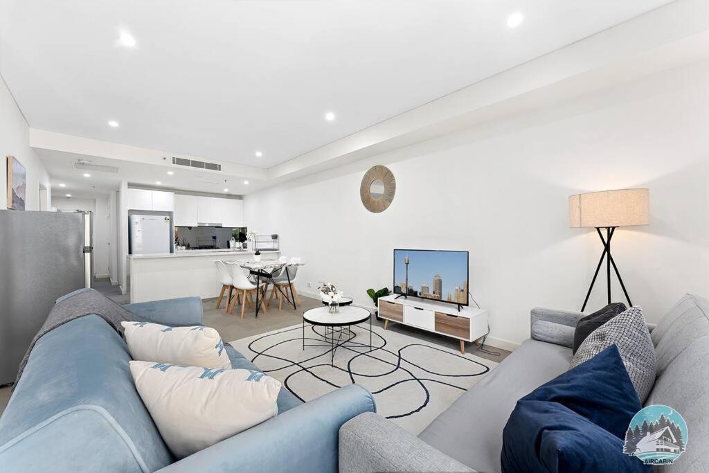 悉尼Aircabin - Mascot - Free Parking - 2 Beds Apt的一间带蓝色沙发的客厅和一间厨房