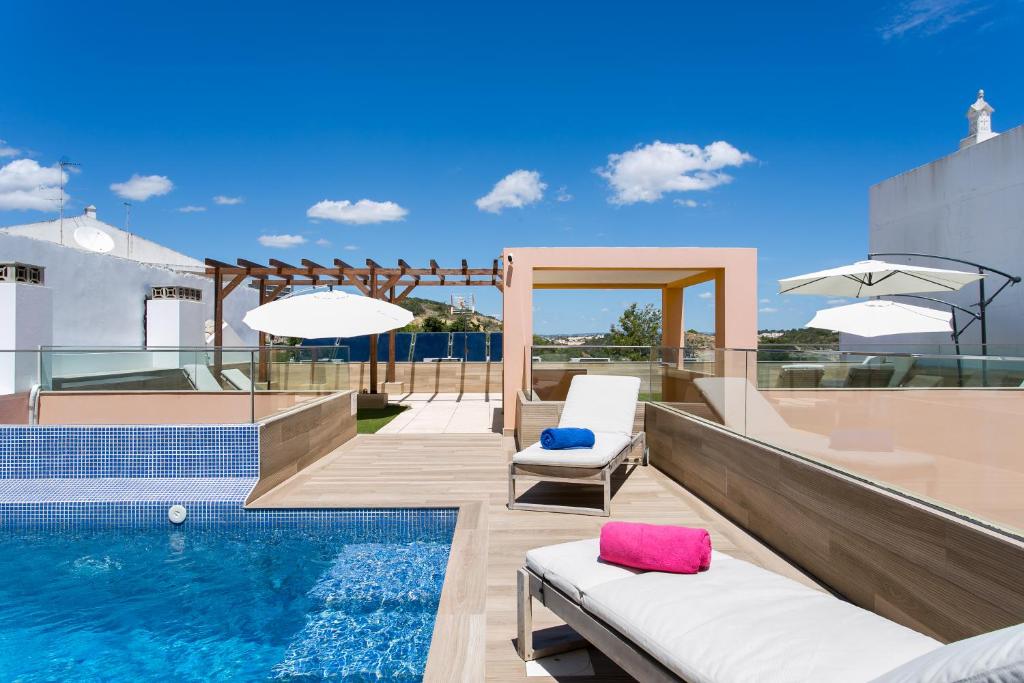 阿尔布费拉Casa Amarela Guesthouse的一个带2把躺椅的游泳池和一个游泳池