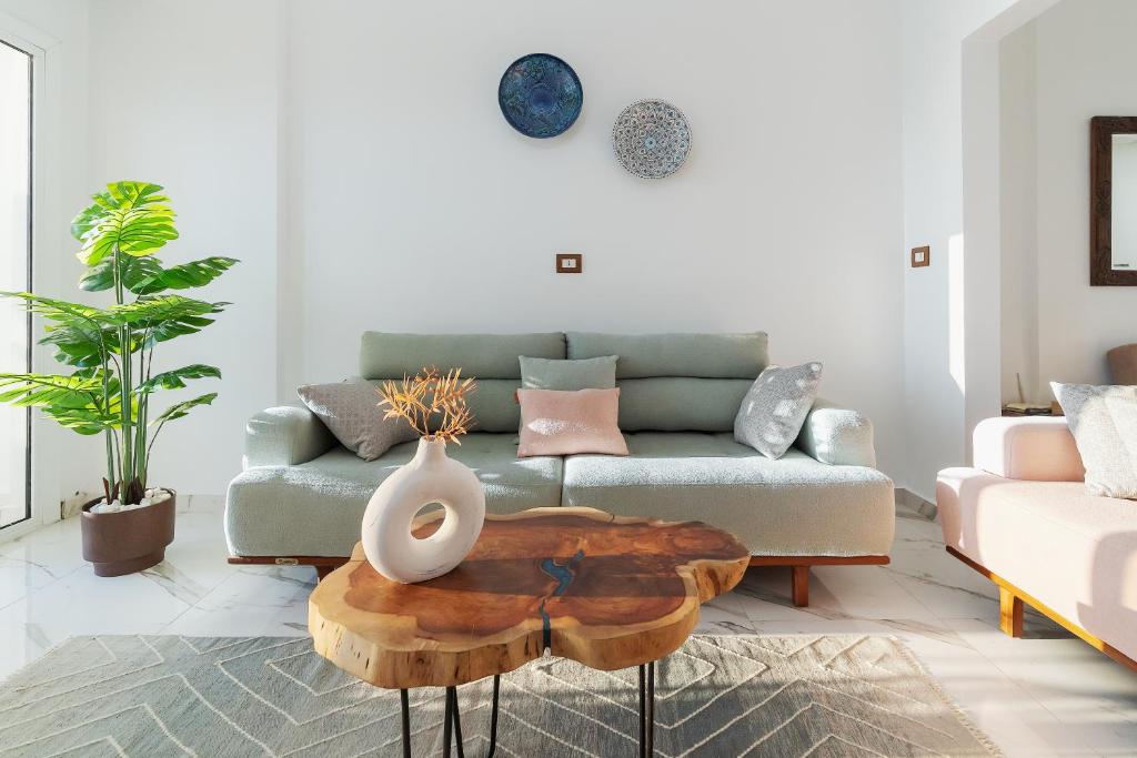 亚历山大Nabeel Homes - Seaview Condo - SP的客厅配有沙发和一张带花瓶的桌子