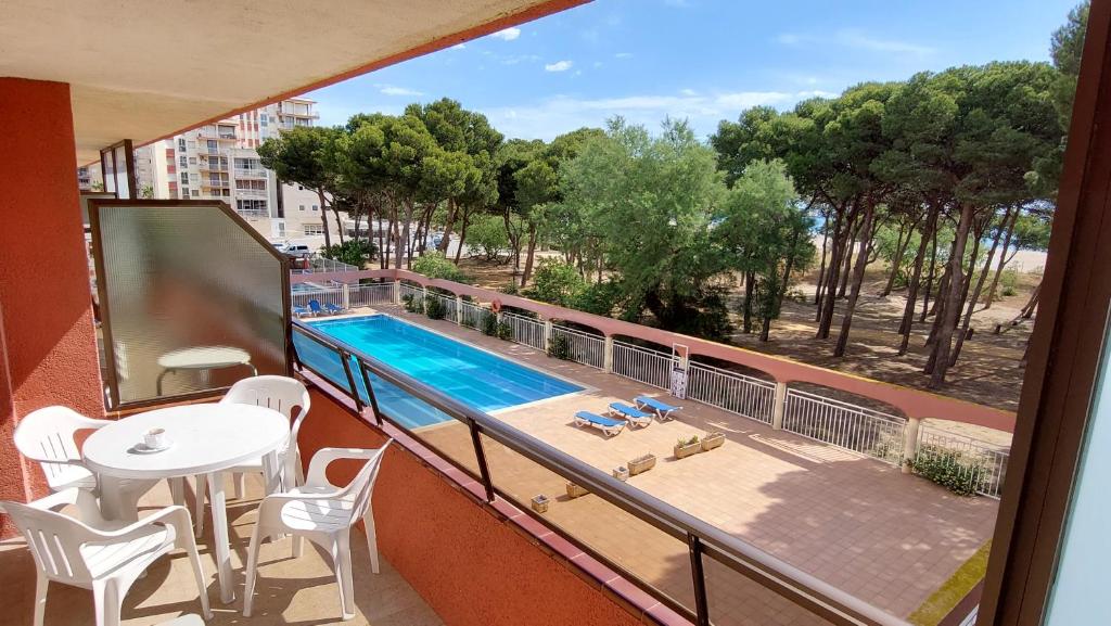 埃斯塔蒂特Primera línea y vistas al mar con piscina的阳台设有游泳池和桌椅。