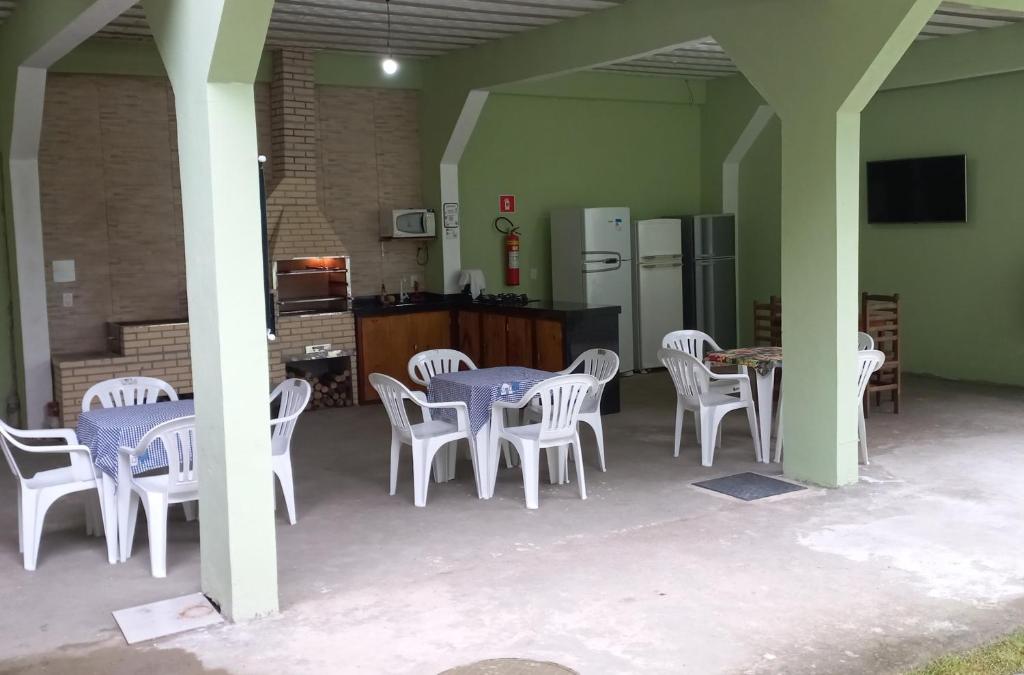 帕拉蒂pousada Cantinho da mata的一间带白色桌椅的厨房和一间带冰箱的厨房