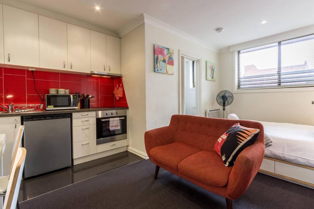 墨尔本Studio Apartment in the heart of Fitzroy的客厅配有红色的沙发和床。