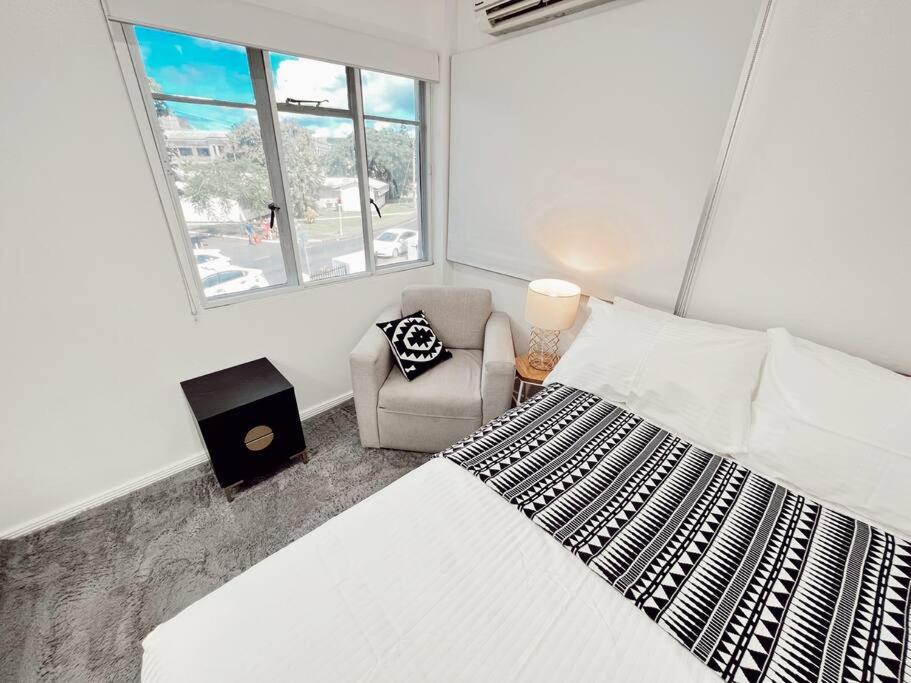 苏瓦Gladstone Gem 3 - Suva CBD 2bd Apt的卧室配有床、椅子和窗户。
