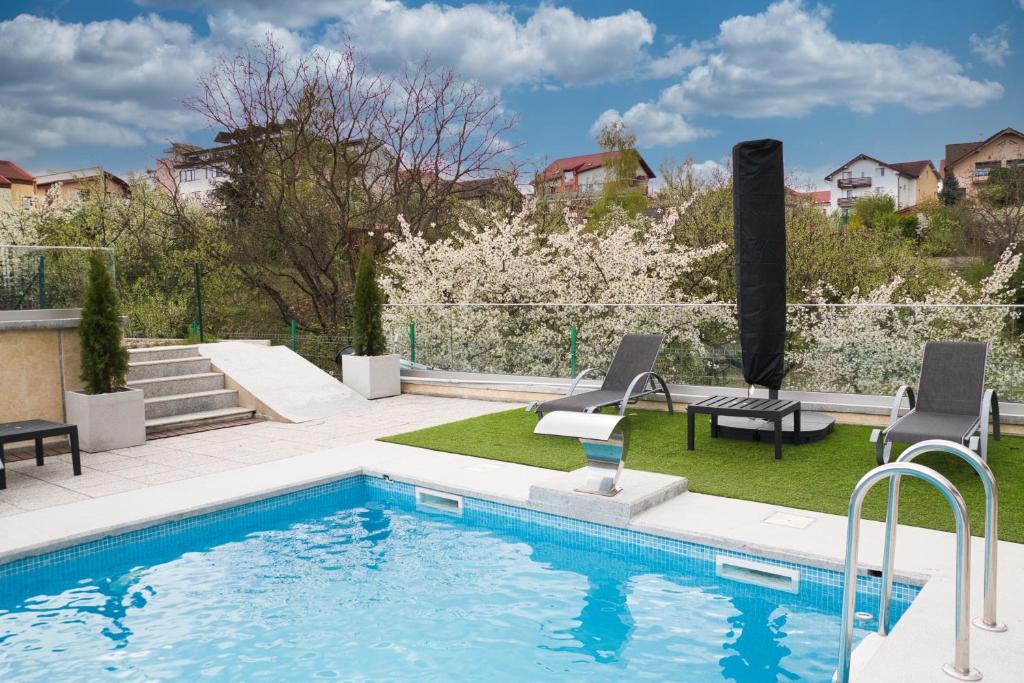 克卢日-纳波卡Panorama Deluxe Aparthotel的庭院旁带两把椅子的游泳池