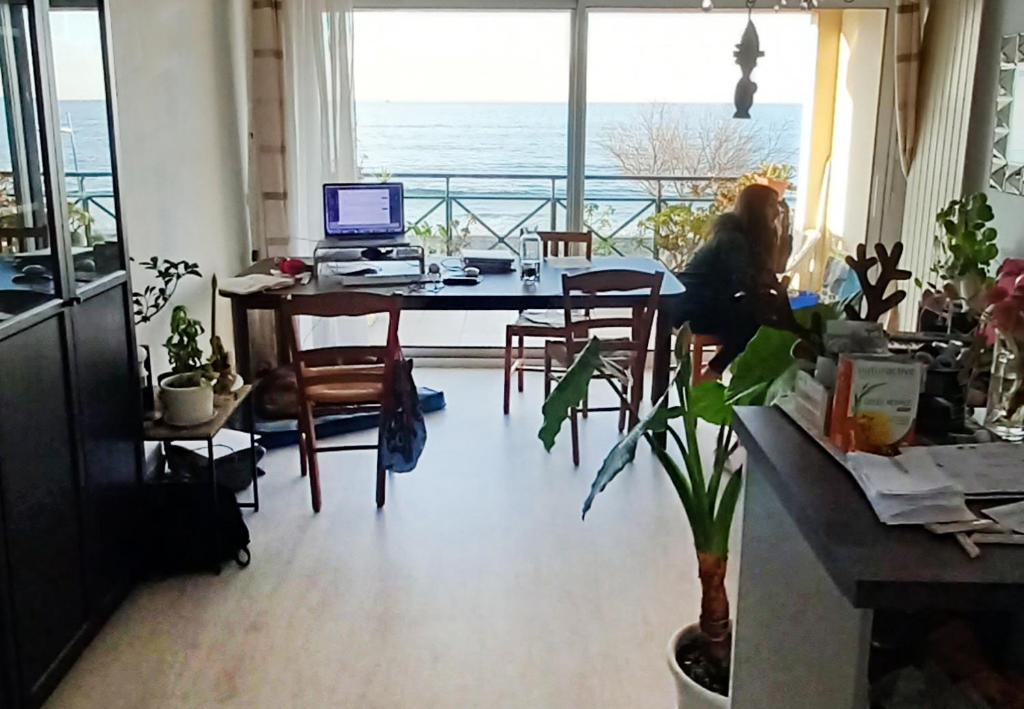 昂代Appartement bord de mer très lumineux 2/4 pers. - Vue inoubliable的坐在桌子上的女人,在屋子里用电脑