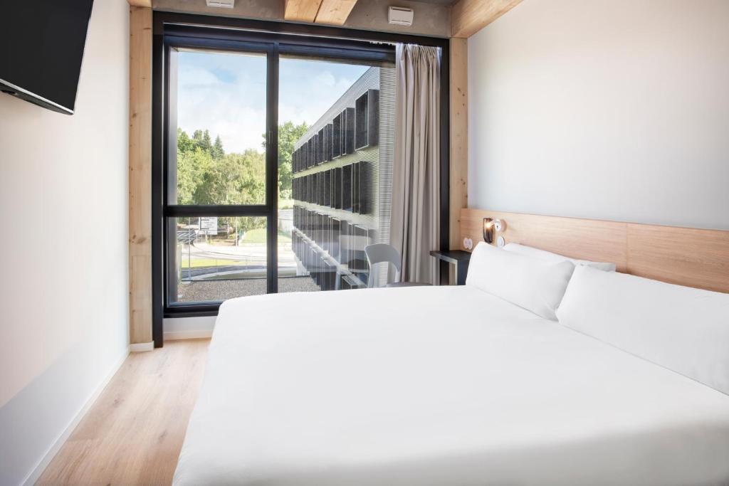 吉马良斯B&B HOTEL Guimarães的卧室设有白色的床和大窗户
