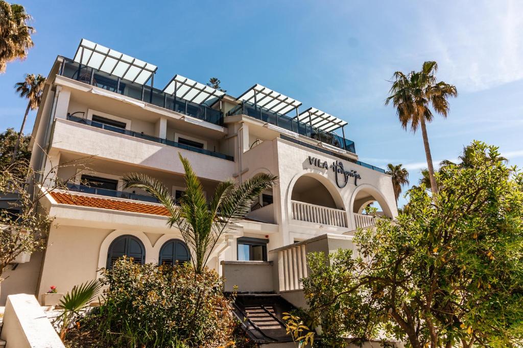 赫尔采格诺维Hotel Vila Hedonija的一座前面有棕榈树的建筑