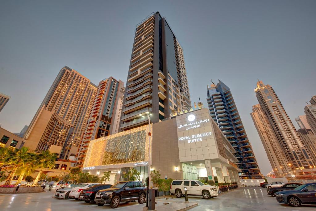 迪拜Royal Regency Suites Marina的停车场内有车辆停放的高楼