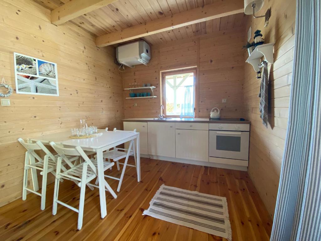斯瓦热沃Morska Osada Swarzewo的小屋内的厨房配有白色的桌椅