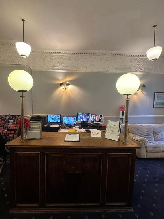伦敦Thanet Hotel Annex的一张桌子,上面有三台显示器和两盏灯