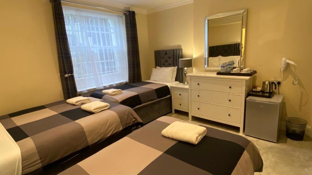 伦敦Prime Inn的一间卧室配有两张床、一个梳妆台和镜子