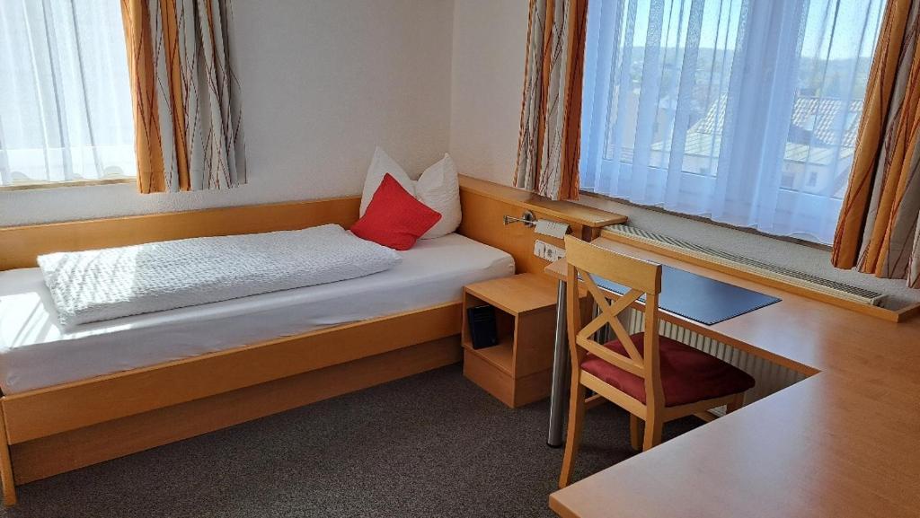 伯布林根BB城市酒店的一间卧室配有一张带书桌的床和红色枕头