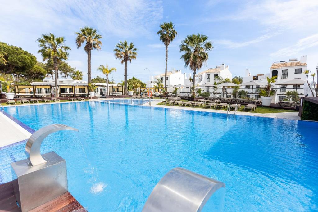 维拉摩拉Apartamentos Honorio - Pool and Garden的一座棕榈树和建筑的大型游泳池