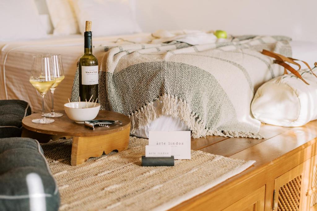 林都斯ARTE LINDOS SUITES的一张带一瓶葡萄酒和一杯葡萄酒的床
