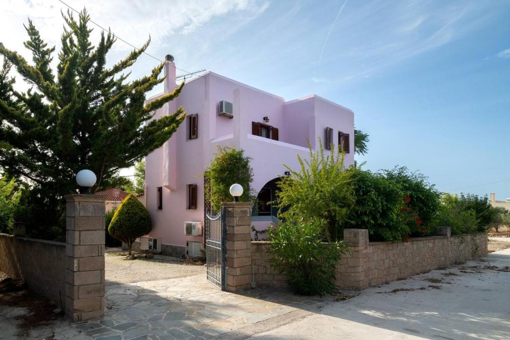 KhlóïNorma’s House的粉红色的房子,前面有栅栏