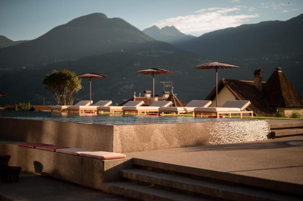 梅拉诺穆彻勒酒店的一个带躺椅和遮阳伞的游泳池