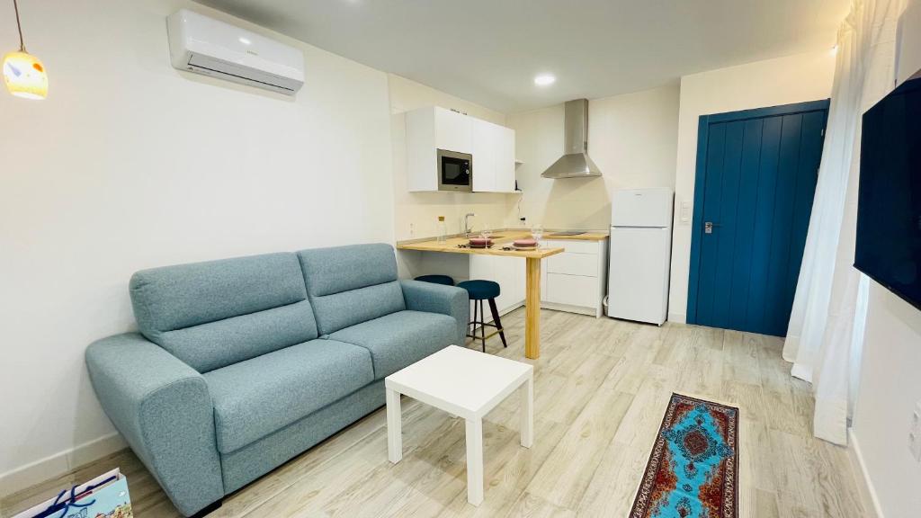 巴达霍斯Apartamentos BRAVO MURILLO con garaje en centro histórico的一间带蓝色沙发的客厅和一间厨房