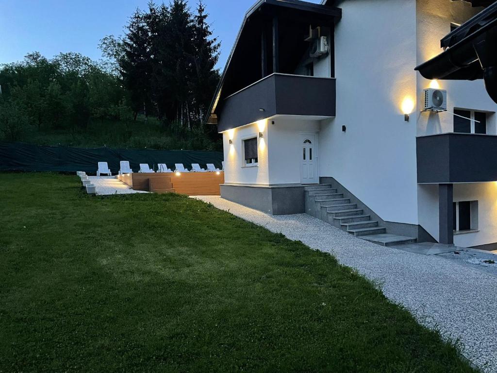 萨格勒布Vila s bazenom deluxe - GTI的白色的建筑,有椅子和草地庭院