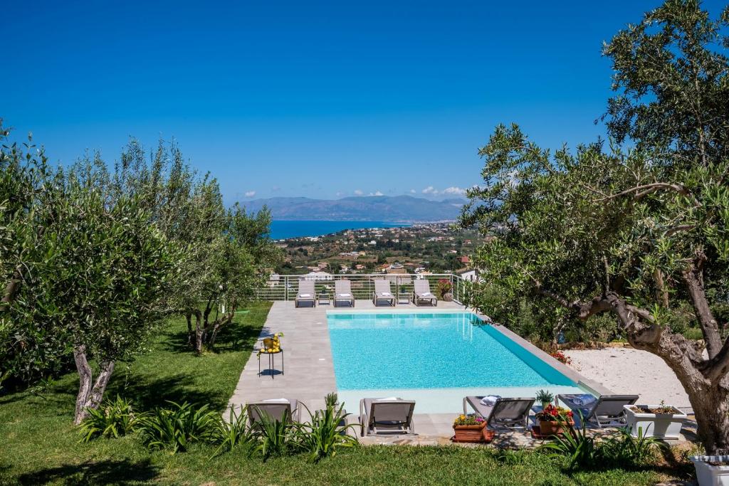 卡斯泰拉马莱Villa Maria con piscina e vista mare的庭院内的游泳池,带椅子和树木