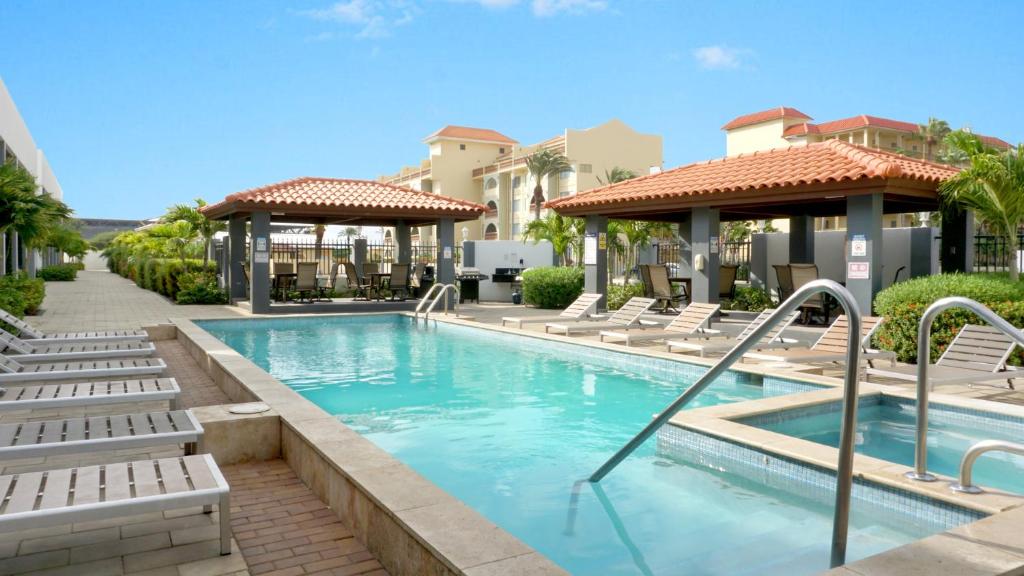 棕榈滩Arena Condominium Aruba的一个带躺椅的游泳池,一个度假村