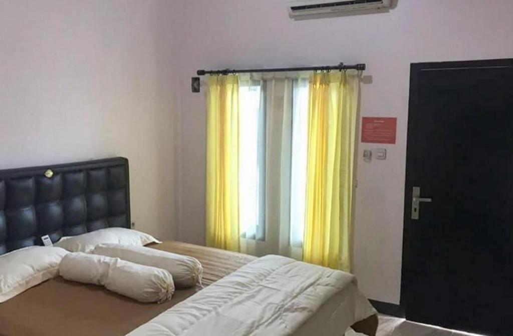 梅劳克Kost Haji Naini的一间卧室设有床和黄色窗帘的窗户
