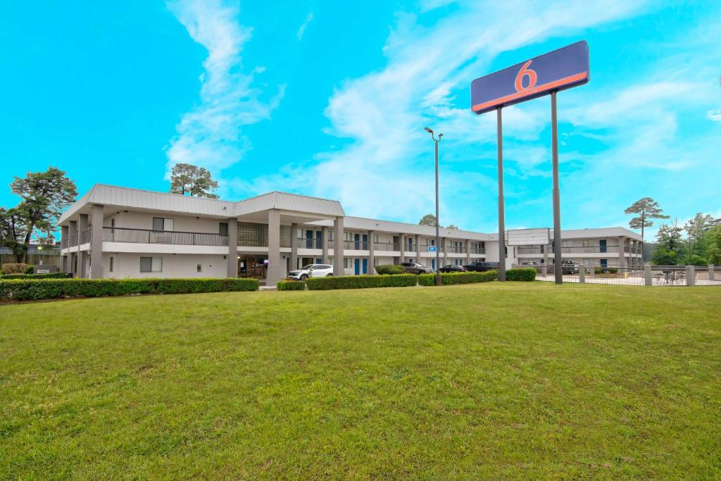 特克萨卡纳-德克萨斯Motel 6 Texarkana, TX的田野前有标志的建筑物