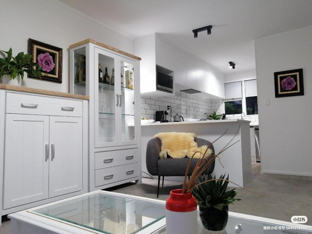 奥克兰Centre Takapuna 2 Beds & Garage & Netflix的白色的厨房配有椅子和玻璃桌