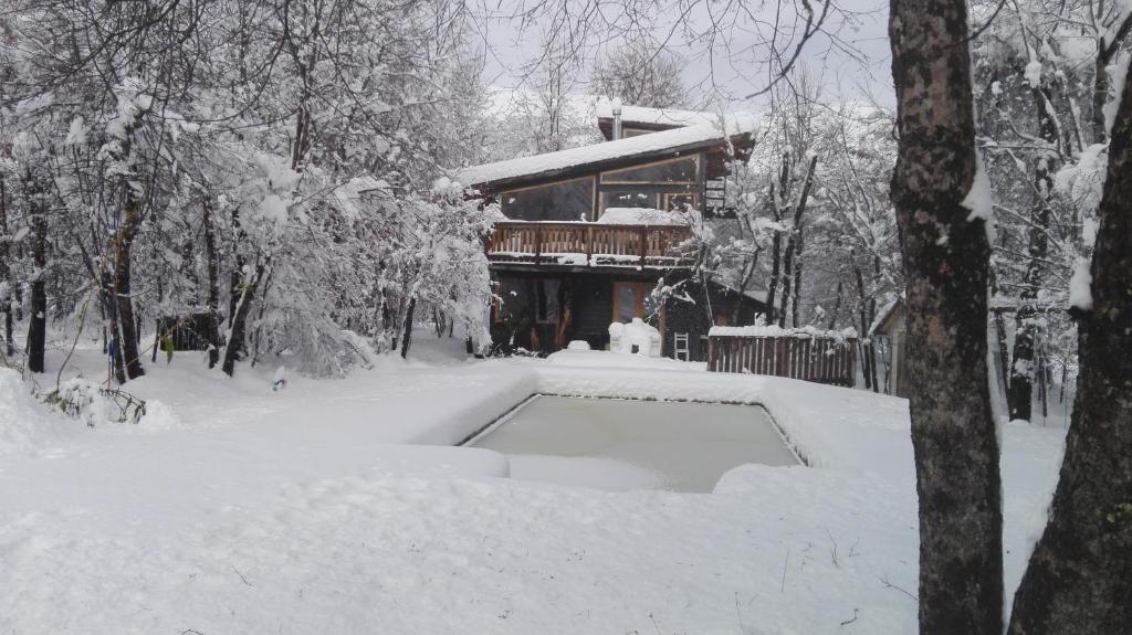 平托Cabaña Lodge los Coihues VALLE LAS TRANCAS# TERMAS DE CHILLAN#NEVADOS DE CHILLAN的一座建筑物前的雪覆盖的房子