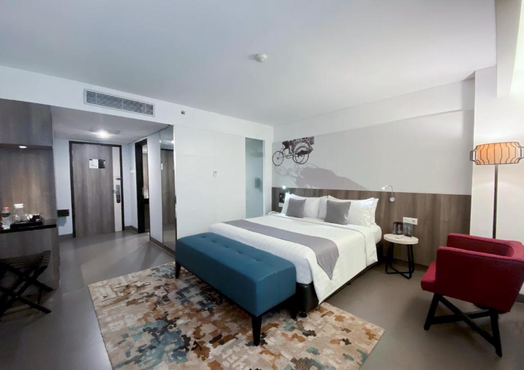 日惹Hotel Neo Malioboro by ASTON的一间卧室配有一张大床和一张红色椅子