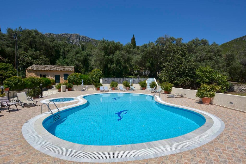 帕莱欧卡斯提撒Marilena Studios And Apartments的一座带椅子和房子的庭院内的大型游泳池