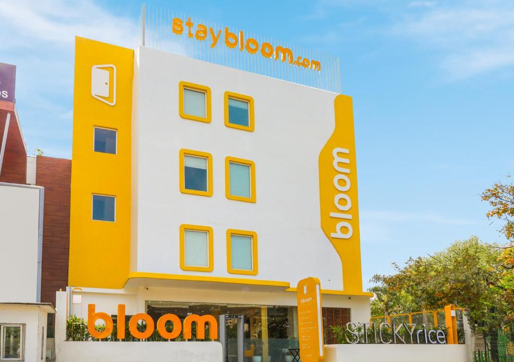 古尔冈Bloom Hotel - Golf Course Road, Sector 43的黄色和白色的建筑,上面有标志