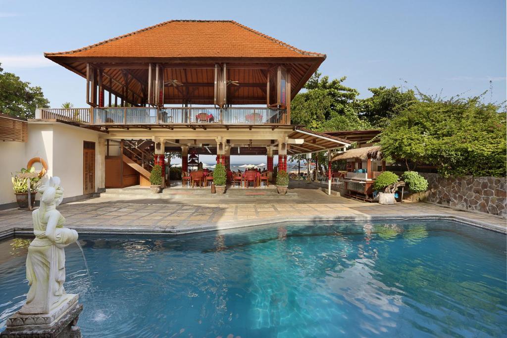 沙努尔若斯帕缇海滩酒店 的一座带建筑物的房子前的游泳池