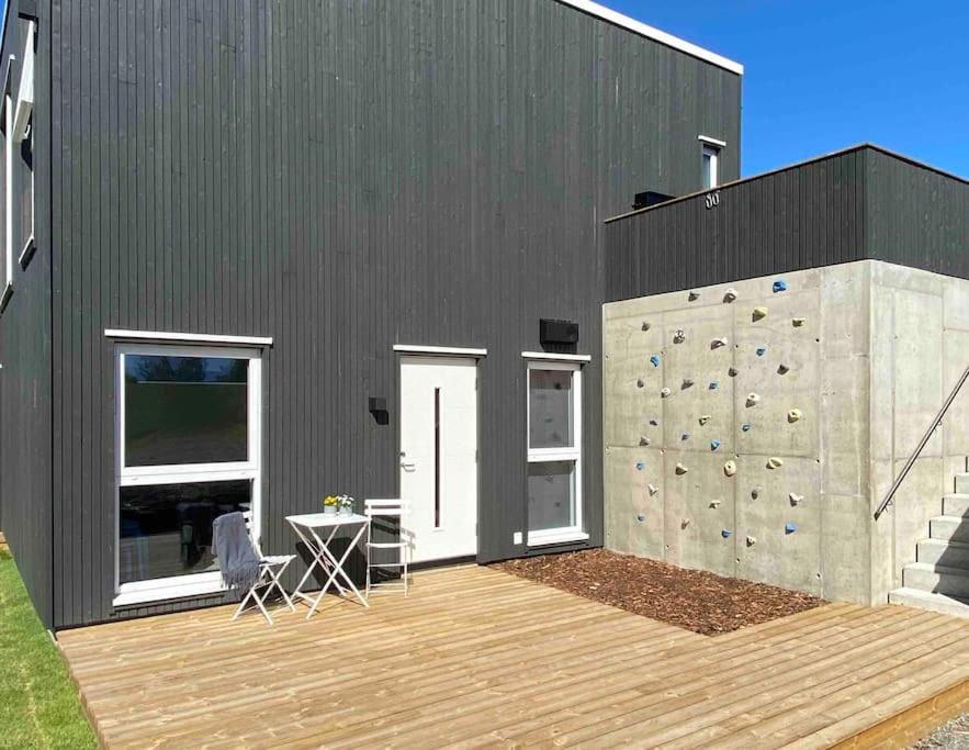 哈山Apartment in Hafjell / Øyer centre.的一座黑色的建筑,设有攀岩墙和木甲板