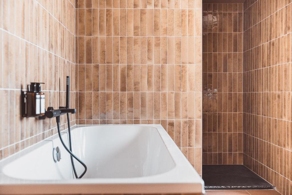 拉姆吉La Voie Lactée的浴室设有浴缸,铺有棕色瓷砖。