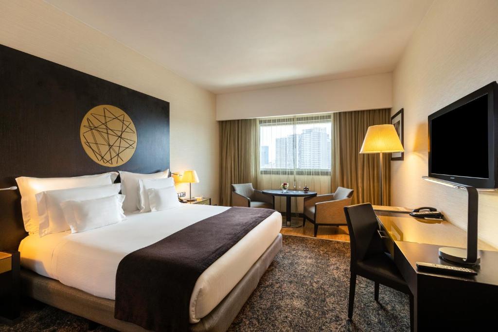 罗安达EPIC SANA罗安达酒店的酒店客房配有一张床、一张书桌和一台电视。