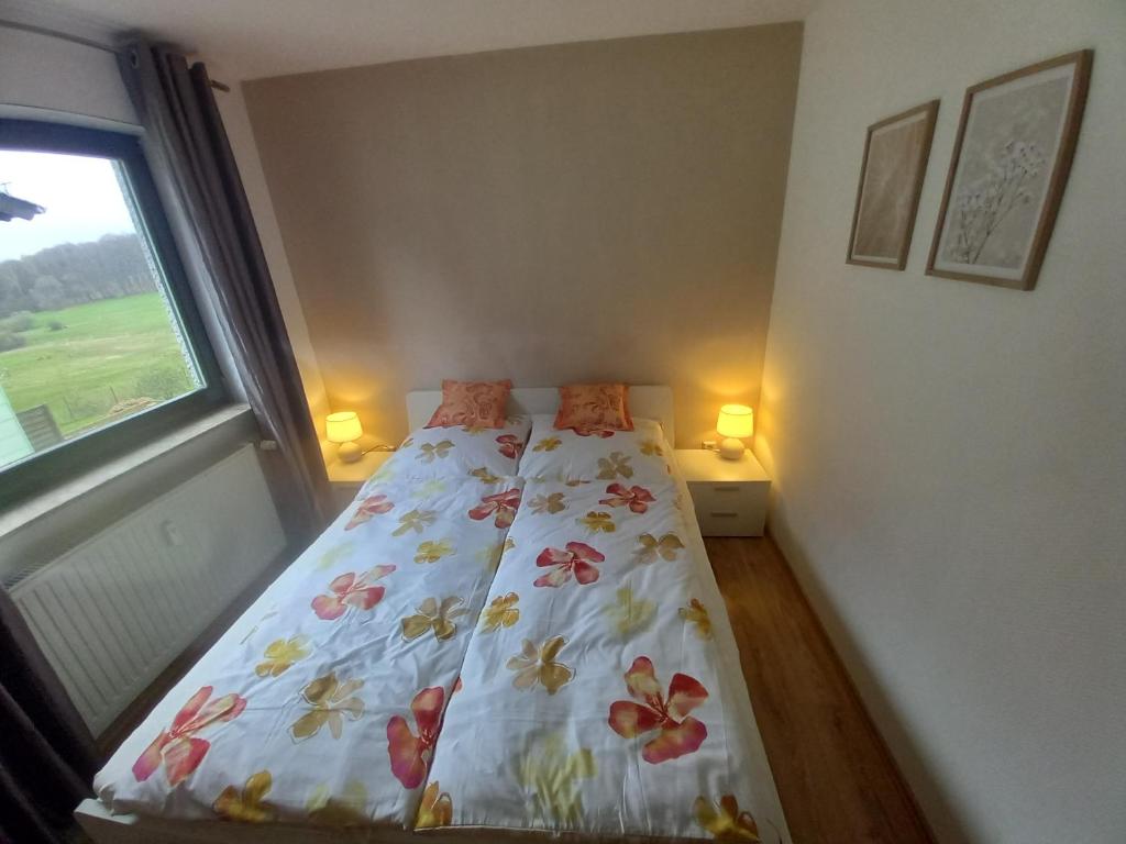 诺费尔登Ferienwohnung Sophia的一间卧室配有一张带花卉床罩的床和窗户。