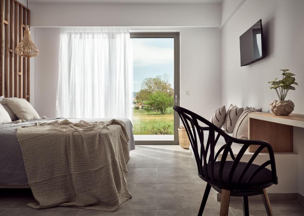 拉加纳斯Cassiopeia Rooms & Suites的卧室配有床、椅子和窗户。