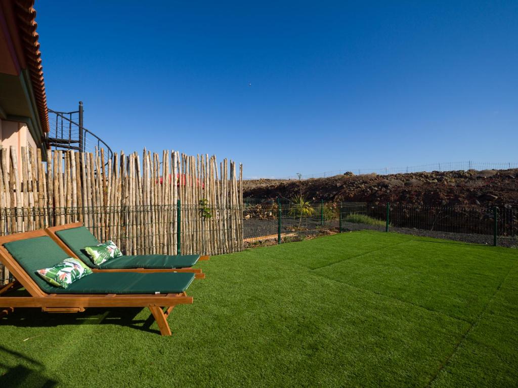 拉奥利瓦Private Terrace Majanicho Home -Garden & Pool的坐在围栏旁草坪上的椅子
