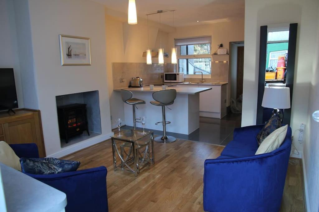康威Charming Mid Terrace Cottage的厨房以及带蓝色椅子和壁炉的客厅。