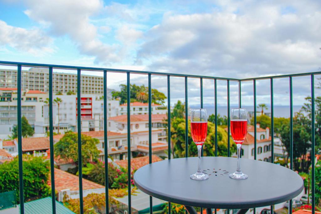 丰沙尔Casal da Penha Apartments的阳台上桌子上放着两杯红葡萄酒