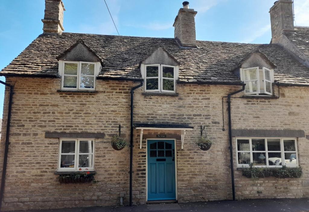 LuckingtonCotswold Cottage Bed & Breakfast的一座带蓝色门窗的旧砖房