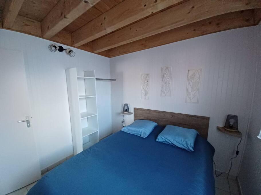 吉福蒙尚波贝尔La Maison Bleu du Lac的一间卧室配有一张蓝色的床和木制天花板